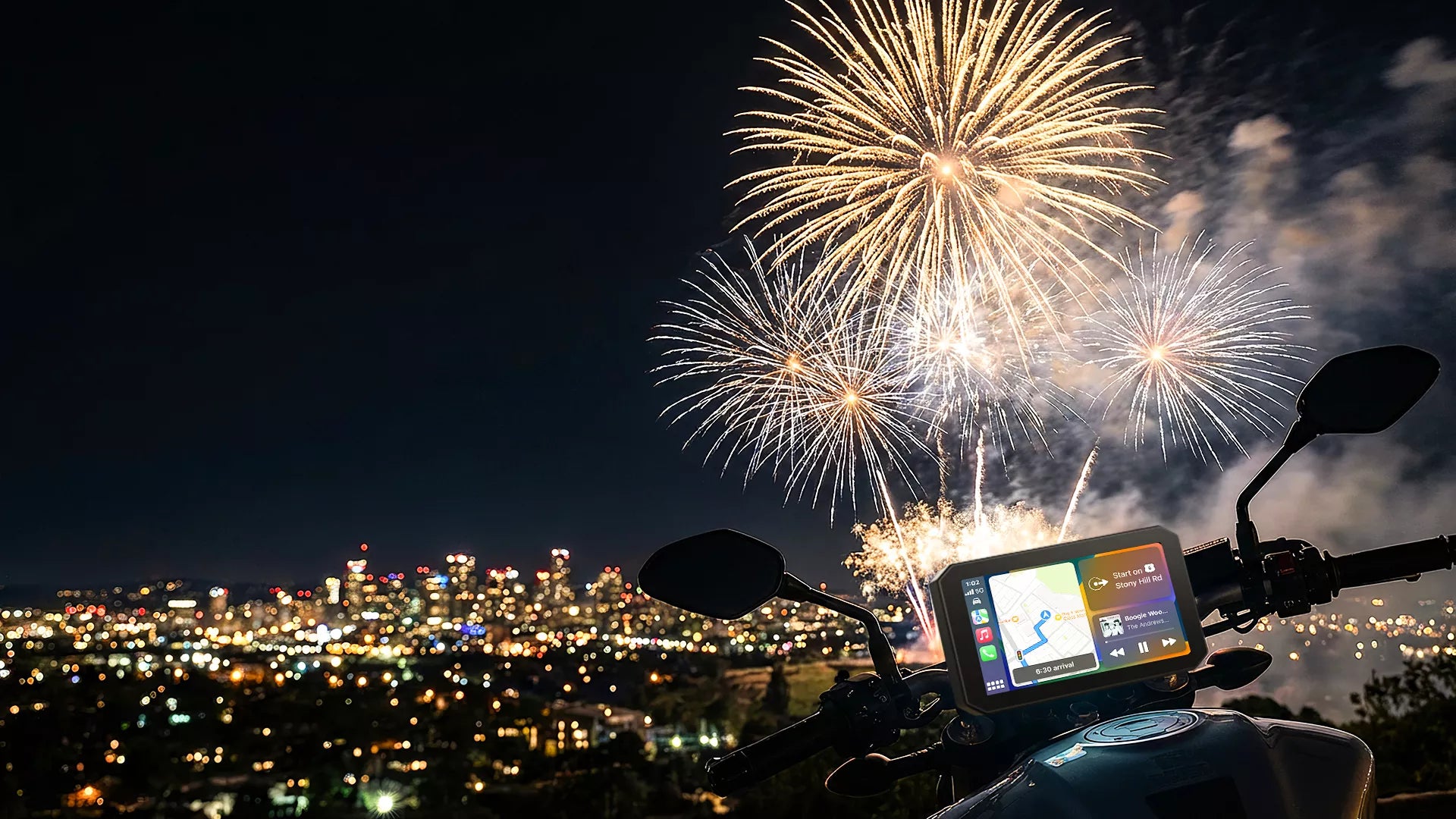 Fireworks over a cityscape with a motorcycle and Aoocci GPS device in the foreground.